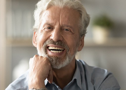 An older smiling man who’s just gotten dentures