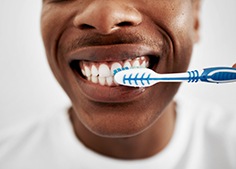 Woman in red-orange shirt admiring reflection in handheld mirror
Nose-to-neck view of man in white t-shirt brushing his teeth