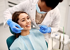 Woman about to have exam performed by dentist in blue gloves