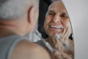 Man looking at teeth in mirror while brushing